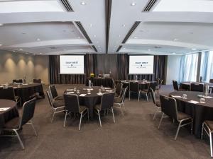 a conference room with tables and chairs and two screens at Quay West Suites Melbourne in Melbourne +114 photos