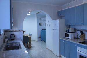 a kitchen with blue cabinets and a white refrigerator at Villa Oliver in Mazarrón