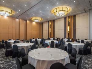 a banquet hall with white tables and chairs and chandeliers at Ibis Gading Serpong in Serpong