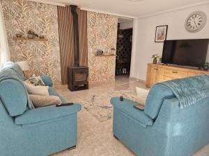 a living room with two blue chairs and a television at Villa Oliver in Mazarrón