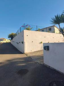 a white wall next to a street with a fence at Dume et Coco F2 55 M2 Vue mer in Taglio-Isolaccio