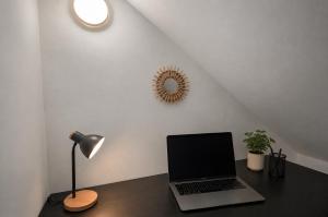 a laptop computer sitting on a desk with a lamp at Chamotte Hyper Centre WIFI Cosy in Bourg-en-Bresse