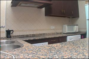a kitchen with a sink and a microwave at Apartamento San José Conil in Conil de la Frontera