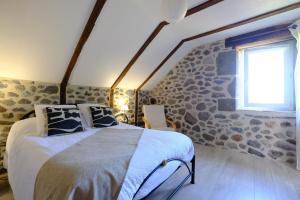 a bedroom with a bed and a stone wall at Ferme de Lamourio in Saint-Cernin