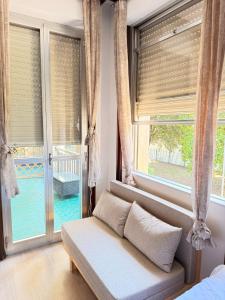 a living room with a couch in front of windows at Happy Hue rooms Malpensa airport in Samarate