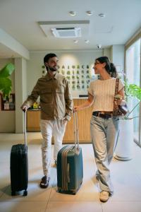 a man and a woman walking with luggage at Bromelia Hotel Boutique in Buenos Aires