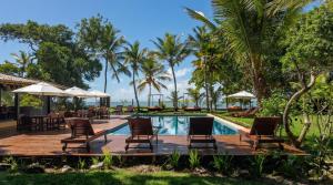 a resort with a pool and chairs and palm trees at Pousada Villa Bianca in Arraial d'Ajuda