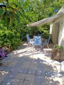 a patio with chairs and a table in the shade at L'ABREUVOIR chez l'habitant 1 Chambre d'hôtes lit 140 et 1chambre d'hôtes 2 lits 90 in Surgères