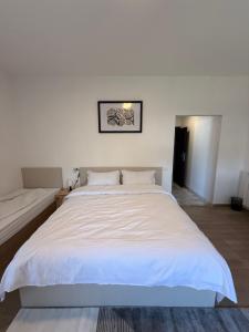 a bedroom with a large bed with white sheets at Happy Hue rooms Malpensa airport in Samarate