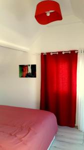 a bedroom with a red bed and a red curtain at House close to the town center and the beach in Quiberon