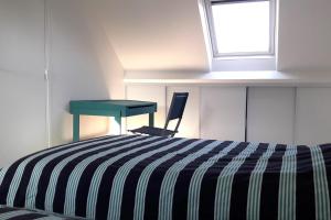 a bedroom with a bed and a desk and a window at House close to the town center and the beach in Quiberon