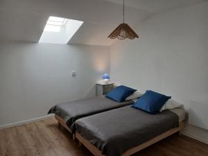 a bedroom with two beds with blue pillows at La Grange Landaise in Laglorieuse