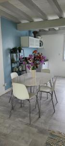 a dining room table with chairs and a vase of flowers at L'annexe des Iris in Chaponost +6 photos