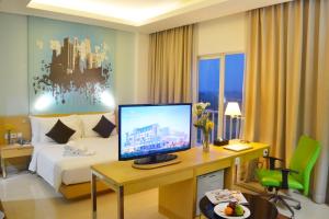 a hotel room with a bed and a desk with a computer at Hotel Santika BSD City-Serpong in Serpong