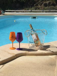 a bottle of wine and two wine glasses next to a pool at Charmante chambre d'hôtes "CARLA" avec piscine, Château de Favas in Bargemon