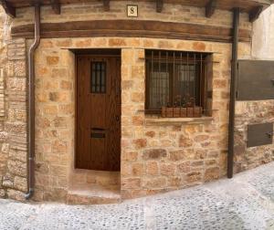 a brick building with a wooden door and a window at Casa O'Tinte in Alquézar