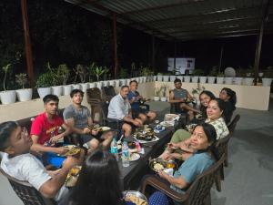 a group of people sitting at tables eating food at Jim Corbett Guest House in Jhirna +75 photos