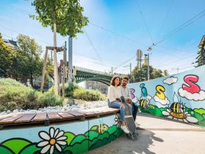 a man and woman sitting on a wall with a skateboard at Ibis Styles Wien City in Vienna