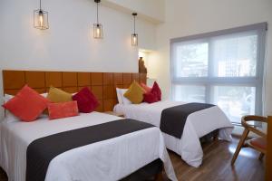 a hotel room with two beds and a window at Hotel Consulado in Guadalajara