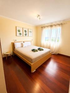 a bedroom with a bed with wooden floors and a window at Ocean Breeze in Caniço