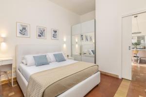 a white bedroom with a large bed with blue pillows at Grafea - Luxury stay in Catania in Catania