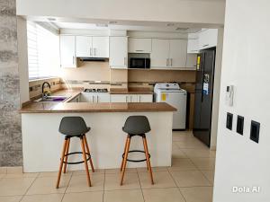 a kitchen with two bar stools at a counter at Tonsupa Playa Almendro in Tonsupa