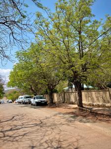 a group of cars parked next to a fence and trees at Mine Lux Rentals in Thabazimbi