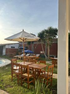 a wooden table and chairs with an umbrella at Hotel Luna Nueva in Colán