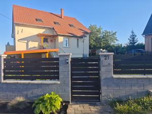 a house with a black fence and a house at Dália Apartman in Tihany