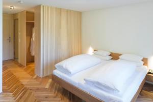 a bedroom with a large bed with white sheets and pillows at Hotel Krone in Au in Au im Bregenzerwald