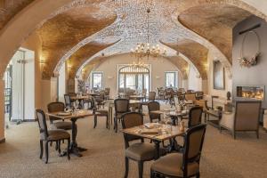 a dining room with tables and chairs and a chandelier at Hôtel La Robéyère - BW Signature Collection in Embrun