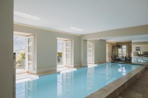 a large swimming pool with blue water in a room with windows at Hôtel La Robéyère - BW Signature Collection in Embrun