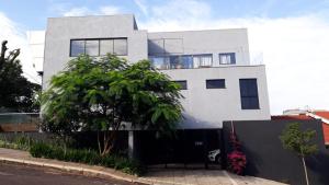 a white house with a tree in front of it at Studio Central IV in Cascavel