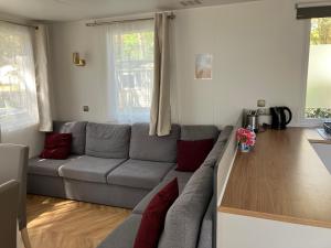 a living room with a gray couch and a wooden table at Grand mobile-home 45M2 au calme et au bord de mer in Saint-Brevin-les-Pins