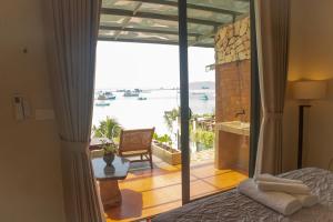 a bedroom with a bed and a view of the water at Chill Beach House in Phú Quốc