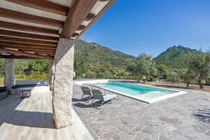 a swimming pool with two chairs and a house at Domu Fama in Tertenìa