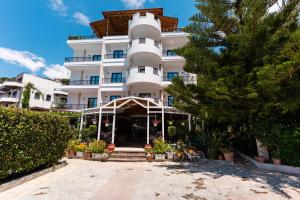 a large white building with a restaurant in front of it at JB Hotel in Sarandë