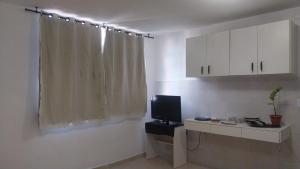 a living room with a television and white cabinets at Hostel OS ETERNOS MONIS in Rio de Janeiro