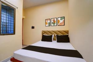 a bedroom with a large white bed with black pillows at Hotel O Utsav In in Jabalpur
