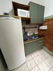 a kitchen with a refrigerator and a microwave at Apartamento central com pátio, 1 quadra do calçadão in Santa Maria