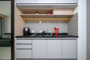 a kitchen with white cabinets and a sink at Estadia Sampa Butantã in São Paulo