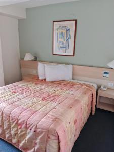 a bedroom with a large bed with a pink comforter at Hotel Lincoln Suites in Caracas