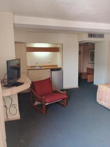 a room with a red chair and a desk and a television at Hotel Lincoln Suites in Caracas