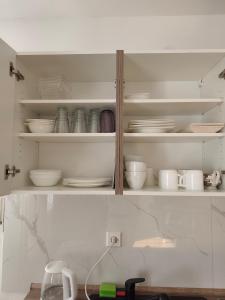 a kitchen cabinet filled with white plates and bowls at Ferienwohnung am Bahnhof Schwerte mit Balkon in Schwerte