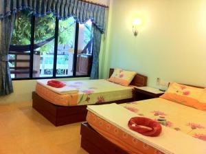 a room with three beds and a window at Black & White Bungalows in Haad Rin