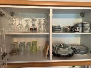 a cabinet filled with glass jars and plates at Ferienwohnung Darosa Alpenliebe in Seeg