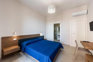 a bedroom with a blue bed and a dining table at Casa Amarantia-Appartamento 2 in Noto