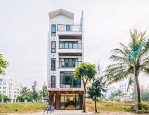 a white building with palm trees in front of it at KEY'N'S HOUSE FLC Sầm Sơn in Sầm Sơn