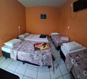 a room with three beds in a room at Pousada Sevilha in Sumaré