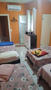 a room with two beds and a dresser in it at Pousada Sevilha in Sumaré
